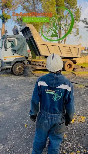 Operator in overalls and hard hat beside a tipper truck on-site