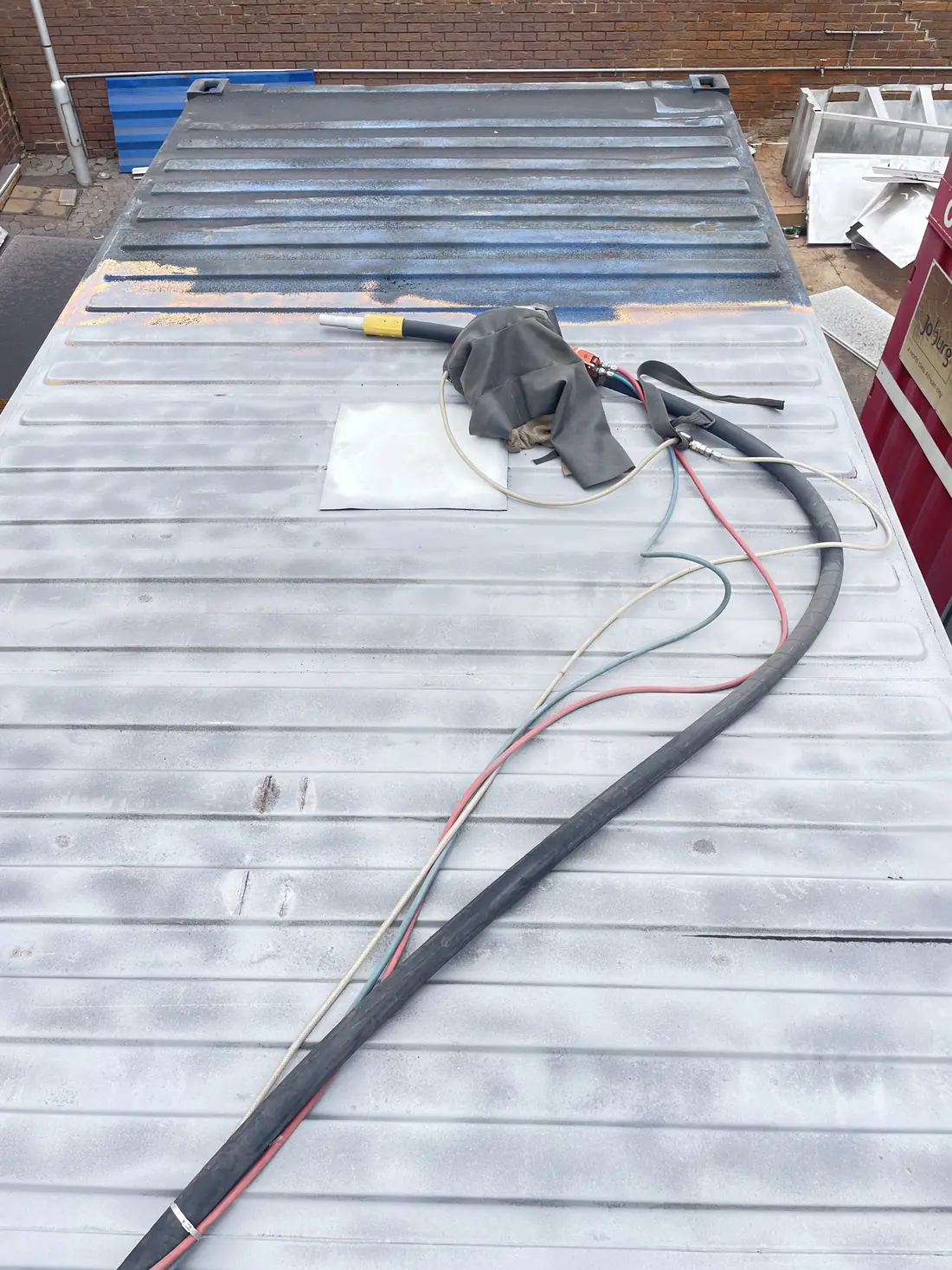 Shipping container roof sandblasted with blast hose lying on the surface
